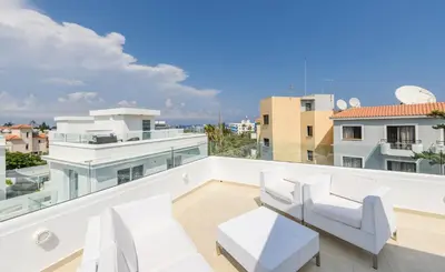 a balcony with white furniture and a view of the city at Green Bay Villa #13 in Protaras