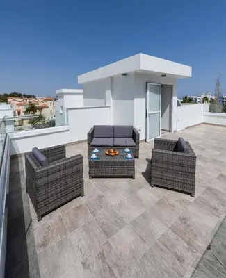 a patio with two chairs and a table on a roof at Green Bay Villa #13 in Protaras