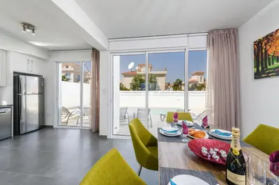 a kitchen and dining room with a table and chairs at Green Bay Villa #13 in Protaras