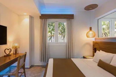 a bedroom with a bed and a desk and a window at So White Beach Resort in Ayia Napa