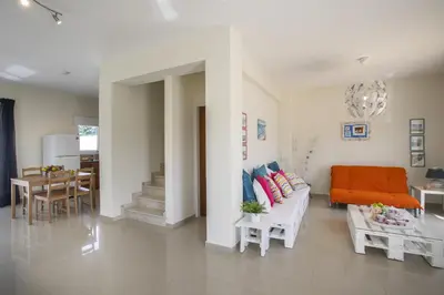 a living room with an orange couch and a table at Protaras Galleria Sunset Villa in Paralimni
