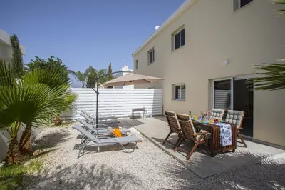 a patio with chairs and a table and an umbrella at Protaras Galleria Sunset Villa in Paralimni