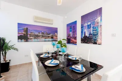 a dining room with a black table and white chairs at Villa Willow Mandali by Ezoria Villas in Protaras