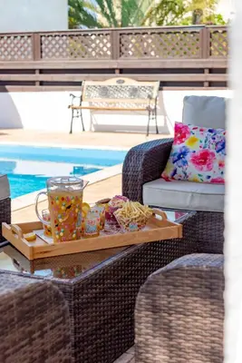 a tray of food sitting on a wicker chair next to a pool at Villa Willow Mandali by Ezoria Villas in Protaras