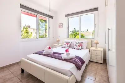 a bedroom with a large white bed with two windows at Villa Willow Mandali by Ezoria Villas in Protaras