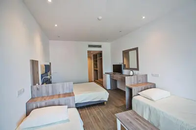 a hotel room with two beds and a desk at Stratovarius Nissi Rooms in Ayia Napa