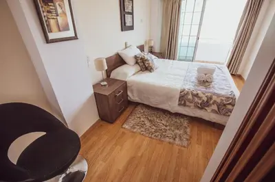 a small bedroom with a bed and a chair at Beach Haven in Larnaka