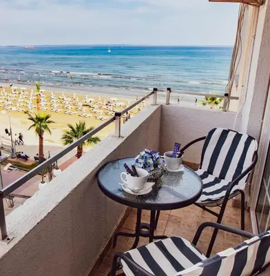a table on a balcony with a view of the beach at Beach Haven in Larnaka