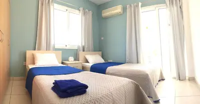 two beds in a room with blue walls and windows at Katerina in Ayia Napa