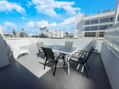 a patio with a table and chairs on a roof at Christina Apartment in Protaras