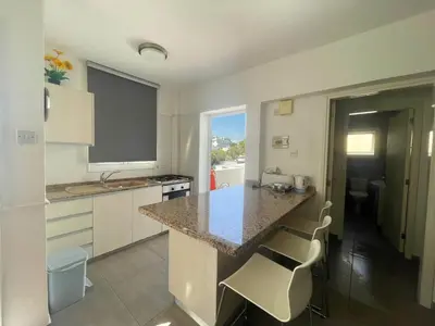 a kitchen with a counter and a island with chairs at Christina Apartment in Protaras