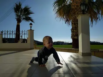a young boy is crawling on a sidewalk at Larnaca Mansion Ideal for 3 Families or more in Larnaka