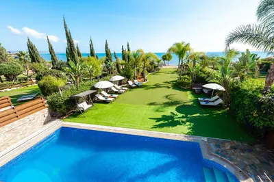 a swimming pool with chairs and umbrellas in a resort at Sea Front Oceanus H2 by Ezoria Villas in Ayia Napa