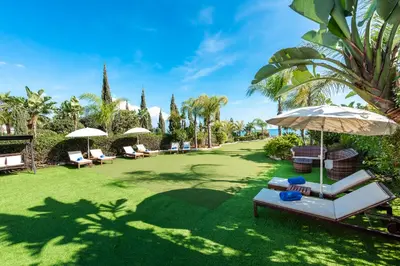 a lawn with chairs and umbrellas in a park at Sea Front Oceanus H2 by Ezoria Villas in Ayia Napa
