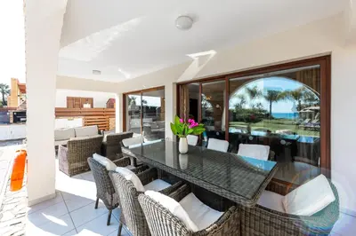 a dining room with a glass table and chairs at Sea Front Oceanus H2 by Ezoria Villas in Ayia Napa