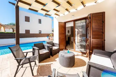 a patio with chairs and a swimming pool at Villa Poseidon by Ezoria Villas in Ayia Napa