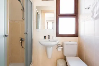 a bathroom with a sink and a toilet and a window at Villa Poseidon by Ezoria Villas in Ayia Napa