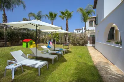 a group of chairs and an umbrella on the grass at Konnos Blue in Protaras