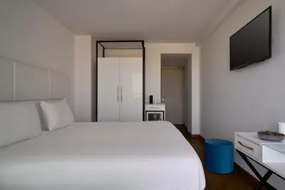 a bedroom with a white bed and a flat screen tv at Hotel Napa Suites (Adults Only) in Ayia Napa