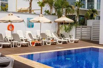 a swimming pool with chairs and umbrellas next to a pool at Milea Hotel in Ayia Napa