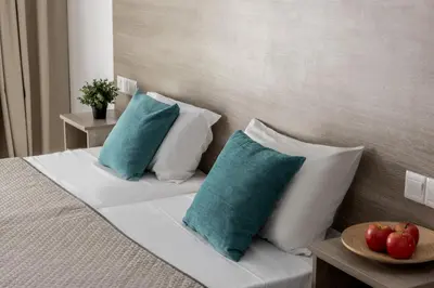 a bed with blue and white pillows and a bowl of fruit at Milea Hotel in Ayia Napa
