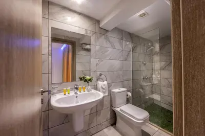 a bathroom with a sink and a toilet and a mirror at Milea Hotel in Ayia Napa