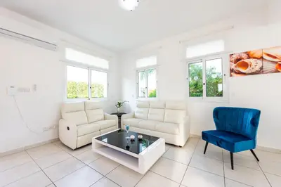 a living room with a couch and a blue chair at Villa Palm Breeze by Ezoria Villas in Protaras