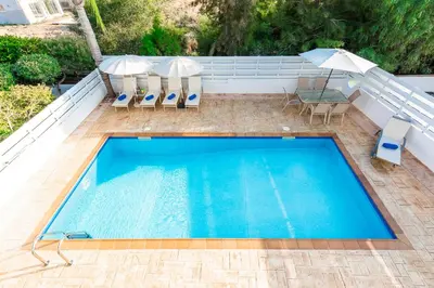 an overhead view of a swimming pool with two umbrellas at Villa Palm Breeze by Ezoria Villas in Protaras