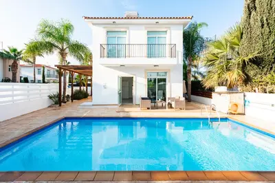 a villa with a swimming pool in front of a house at Villa Palm Breeze by Ezoria Villas in Protaras