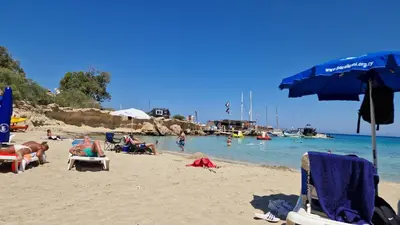 a group of people sitting on a beach at Green Bay Penthouse 2 in Protaras