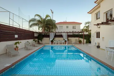 a swimming pool with chairs and a house at Athena Villa in Ayia Napa