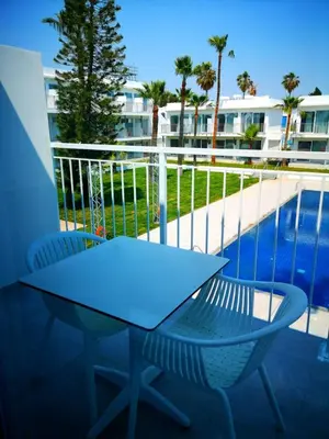 a table and two chairs on a balcony with a pool at Lysithea Hotel in Larnaka