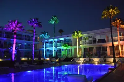 a hotel with palm trees and a pool at night at Lysithea Hotel in Larnaka