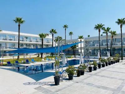 a swimming pool with palm trees and a building at Lysithea Hotel in Larnaka