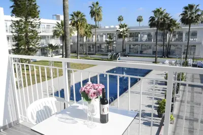 a table with a bottle of wine and flowers on a balcony at Lysithea Hotel in Larnaka