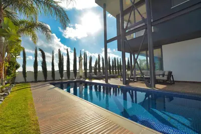 a swimming pool in front of a house with palm trees at White Pearl Villas in Protaras
