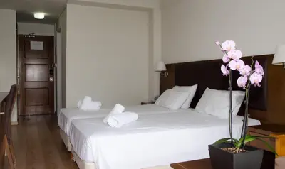 a bedroom with a bed with white sheets and pink flowers at Rodon Hotel and Resort in Agros