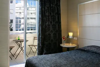 a bedroom with a bed and a window and a table at Cleopatra Hotel in Nicosia