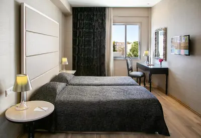 a hotel room with two beds and a desk at Cleopatra Hotel in Nicosia