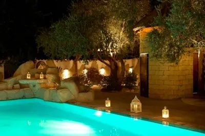 a swimming pool with lights in a yard at night at Cleopatra Hotel in Nicosia