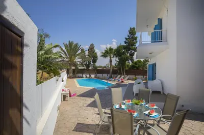 a patio with a table and chairs next to a pool at Villa Serene in Ayia Napa