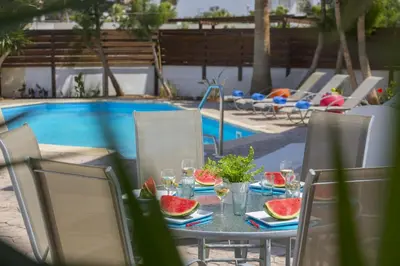 a table with watermelons on it next to a pool at Villa Serene in Ayia Napa