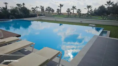 a large swimming pool with blue water and palm trees at Beachfront Luxury Villa Tranquility in Ayia Napa