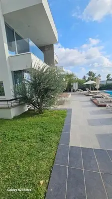 a large building with a walkway in front of a yard at Beachfront Luxury Villa Tranquility in Ayia Napa