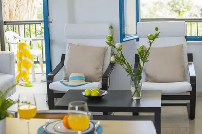 a living room with a table with a vase of flowers at Protaras Ayios Elias Suite in Protaras