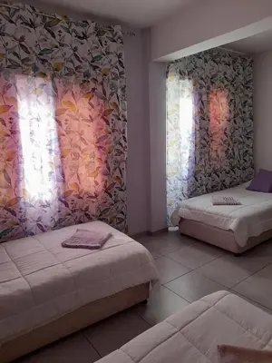 a bedroom with two beds and two windows at Onisillos Hotel in Larnaka