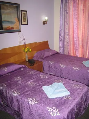 two beds in a room with purple sheets at Onisillos Hotel in Larnaka