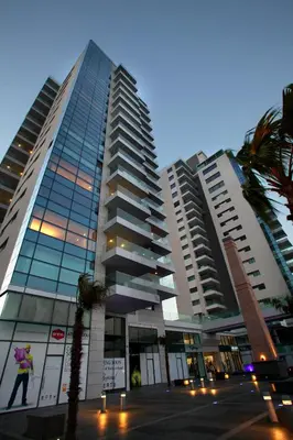 a tall building with a palm tree in front of it at Olympic Residence Deluxe Apartments in Limassol