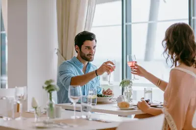 a man and woman sitting at a table with wine glasses at Lebay Beach Hotel in Larnaka