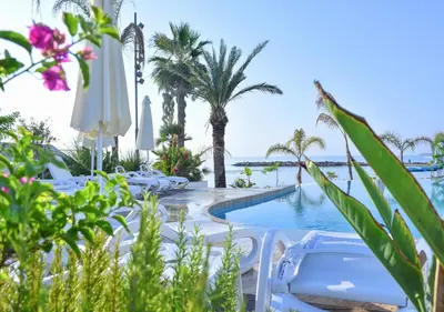 a pool at the resort with chairs and palm trees at Lebay Beach Hotel in Larnaka